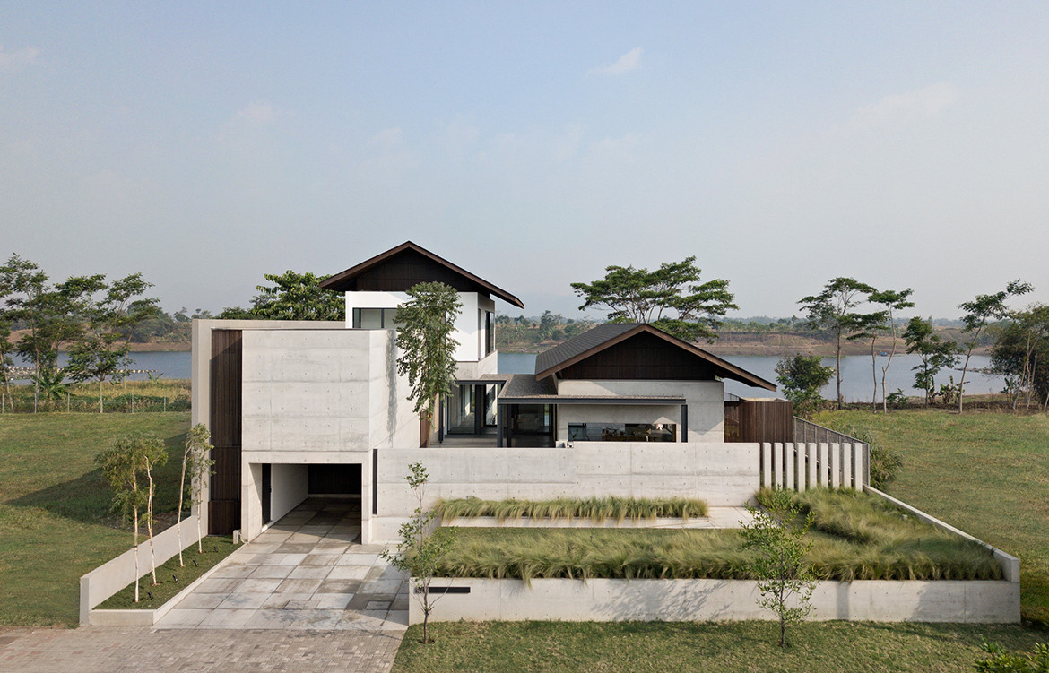 Concealed by concrete perimeter walls, the lakeside Iyashi House by Pranala Associates looks like a private garden city