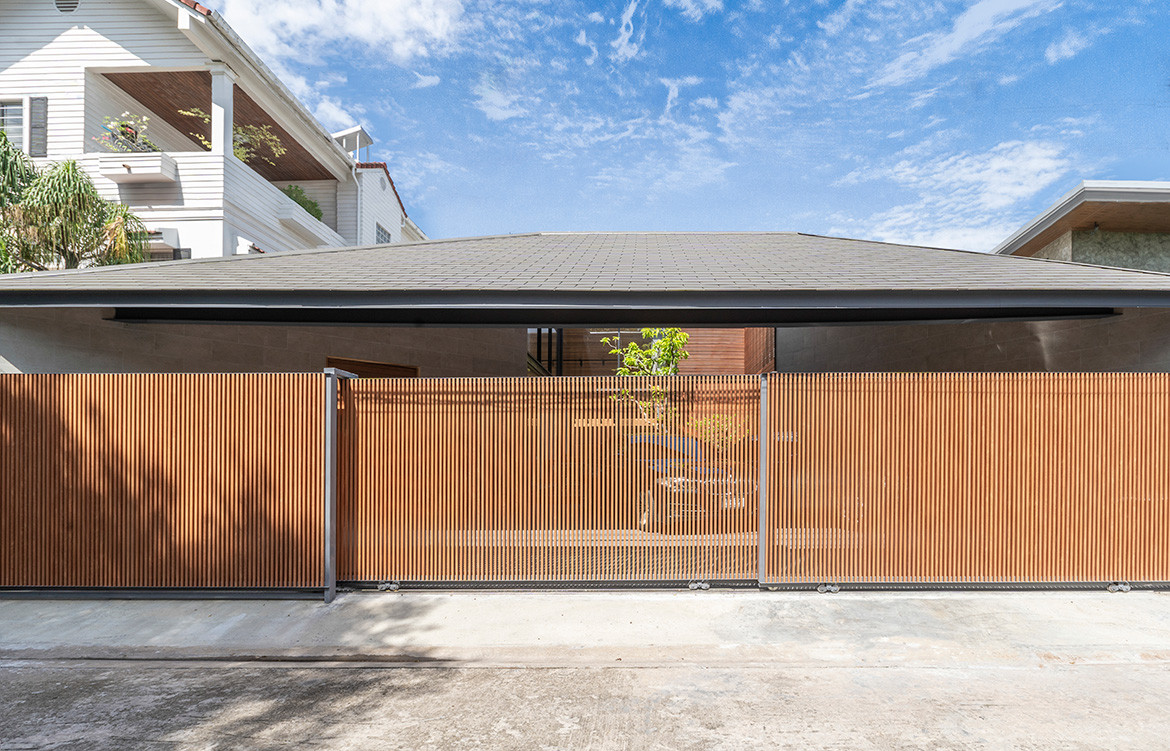 The Roof House by Looklen Architects hides behind a timber gate in a quiet residential street of Bangkok.