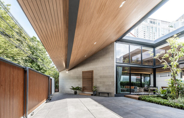 The internal courtyard of The Roof House by Looklen Architects is just visible through a lath timber fence.