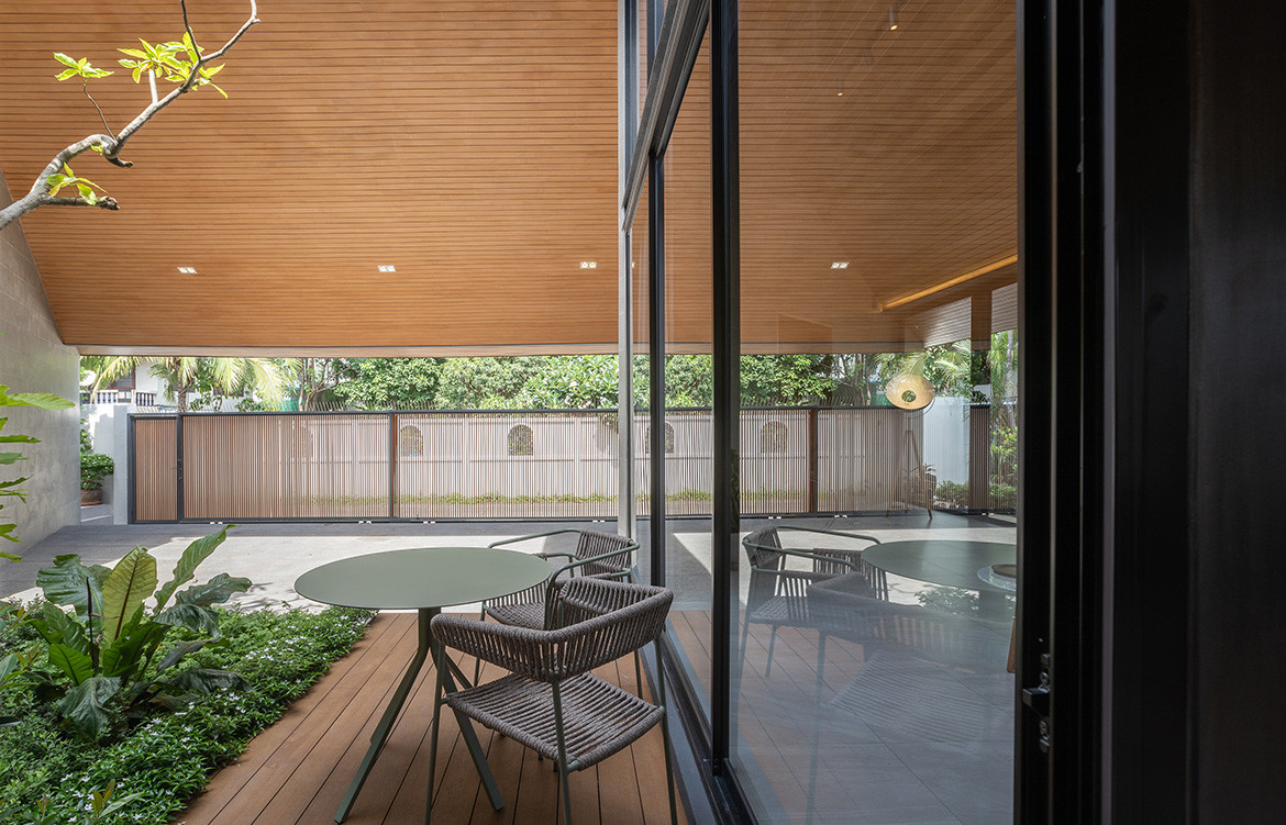 The internal courtyard of The Roof House by Looklen Architects is just visible through a lath timber fence.