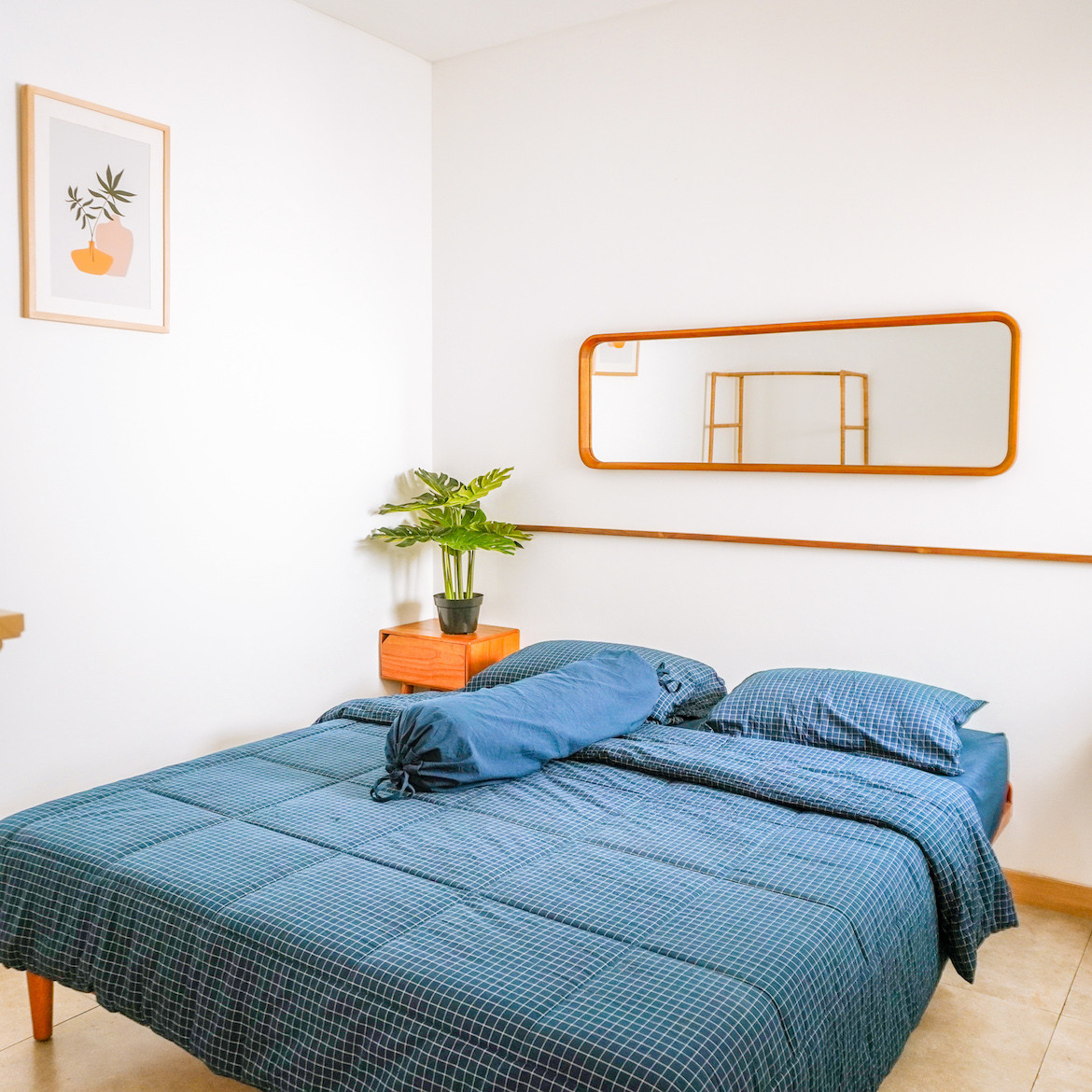 A bed with blue sheets and a mirror above it in Eureka House.