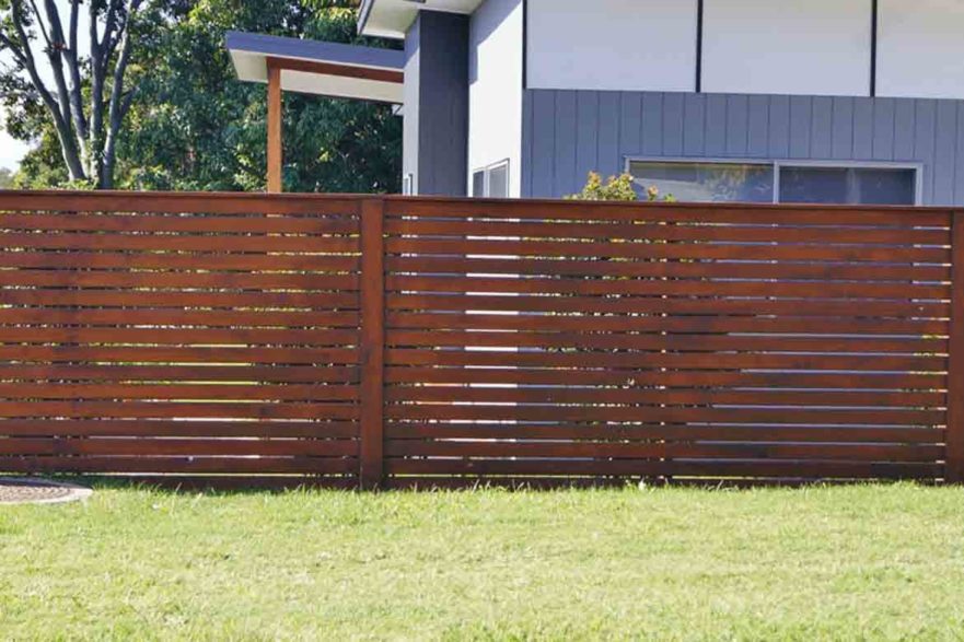 horizontal batten timber fence in backyard with green lawn