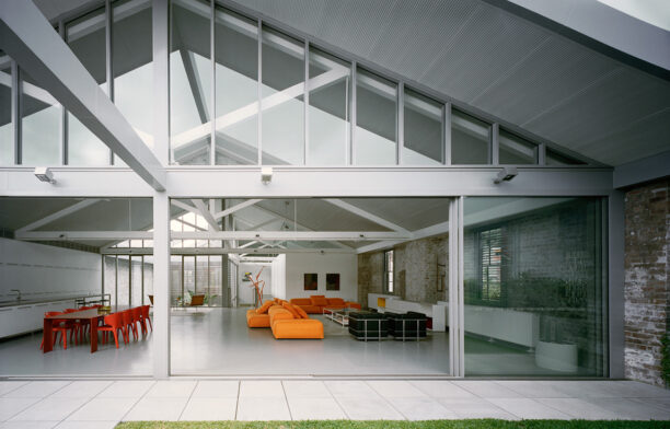 Redfern Warehouse by Ian Moore Architects has a contemporary open plan floor plan configuration and a white, grey, orange, and red colour palette