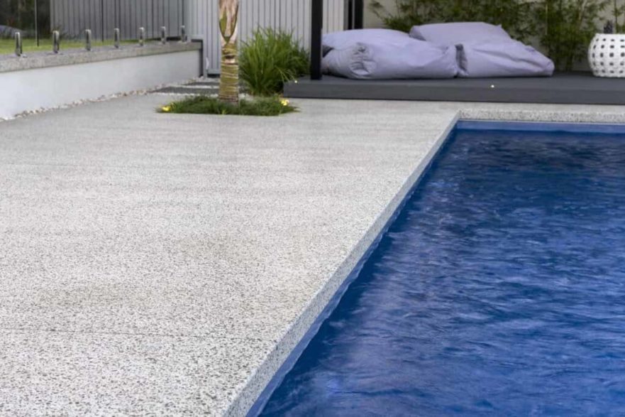 poolside exposed aggregate concrete modern design clean blue pool