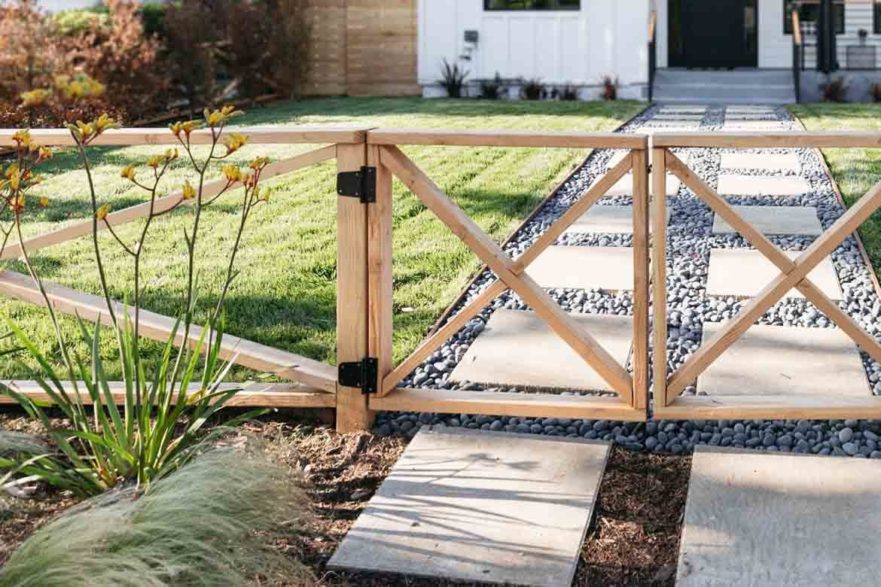 rustic front yard timber fence with stone path and bushes