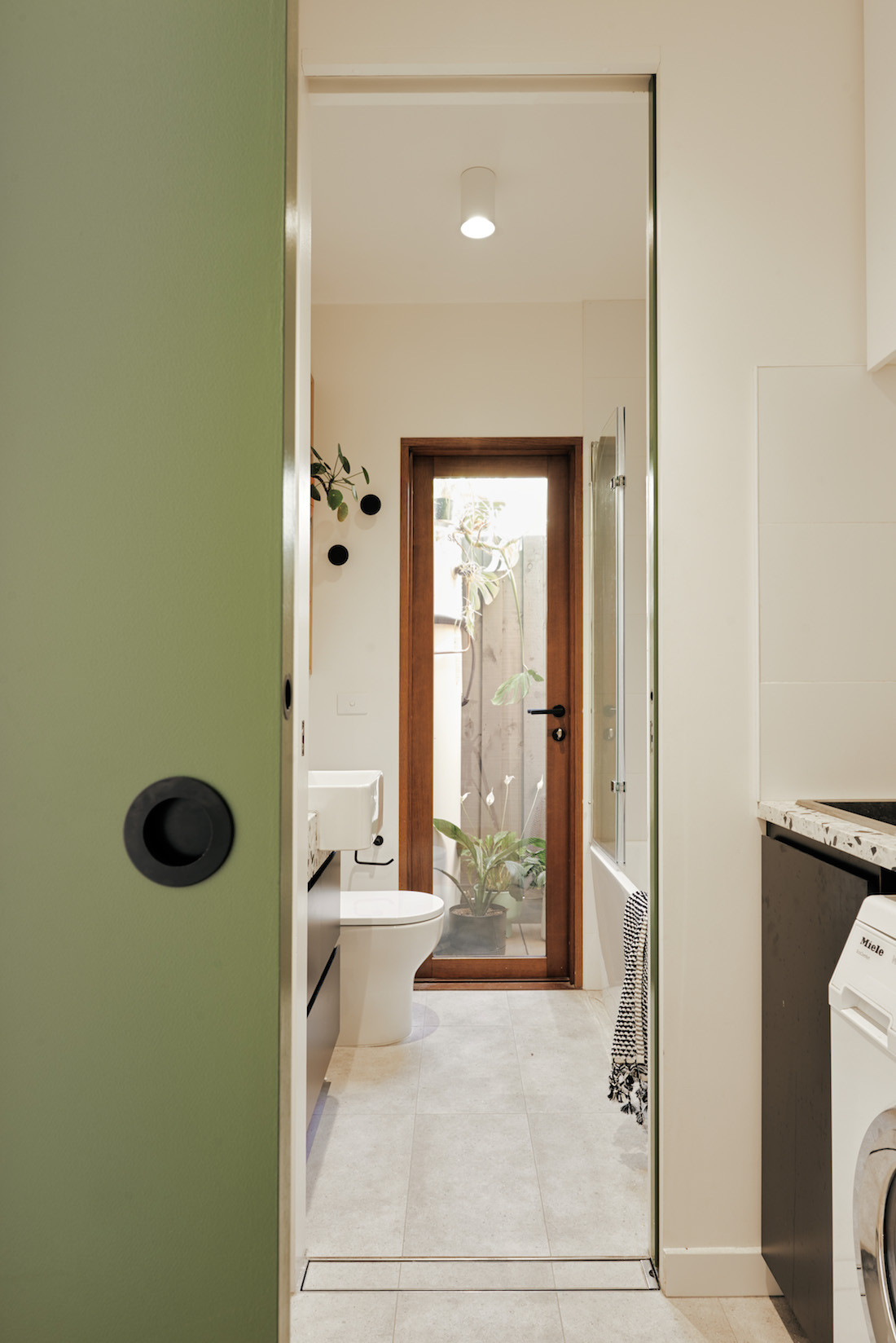 A Dulux coloured Asparagus Green sliding door between the Brunswick home's bathroom and laundry.