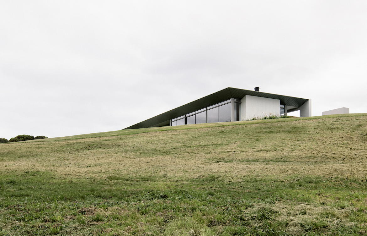 Carr Peninsular House peaks out above a grassy hill.