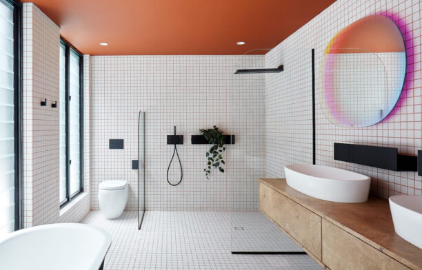The white and orange bathroom with an iridescent mirror by Patricia Urquiola in State of Kin's Shutter House