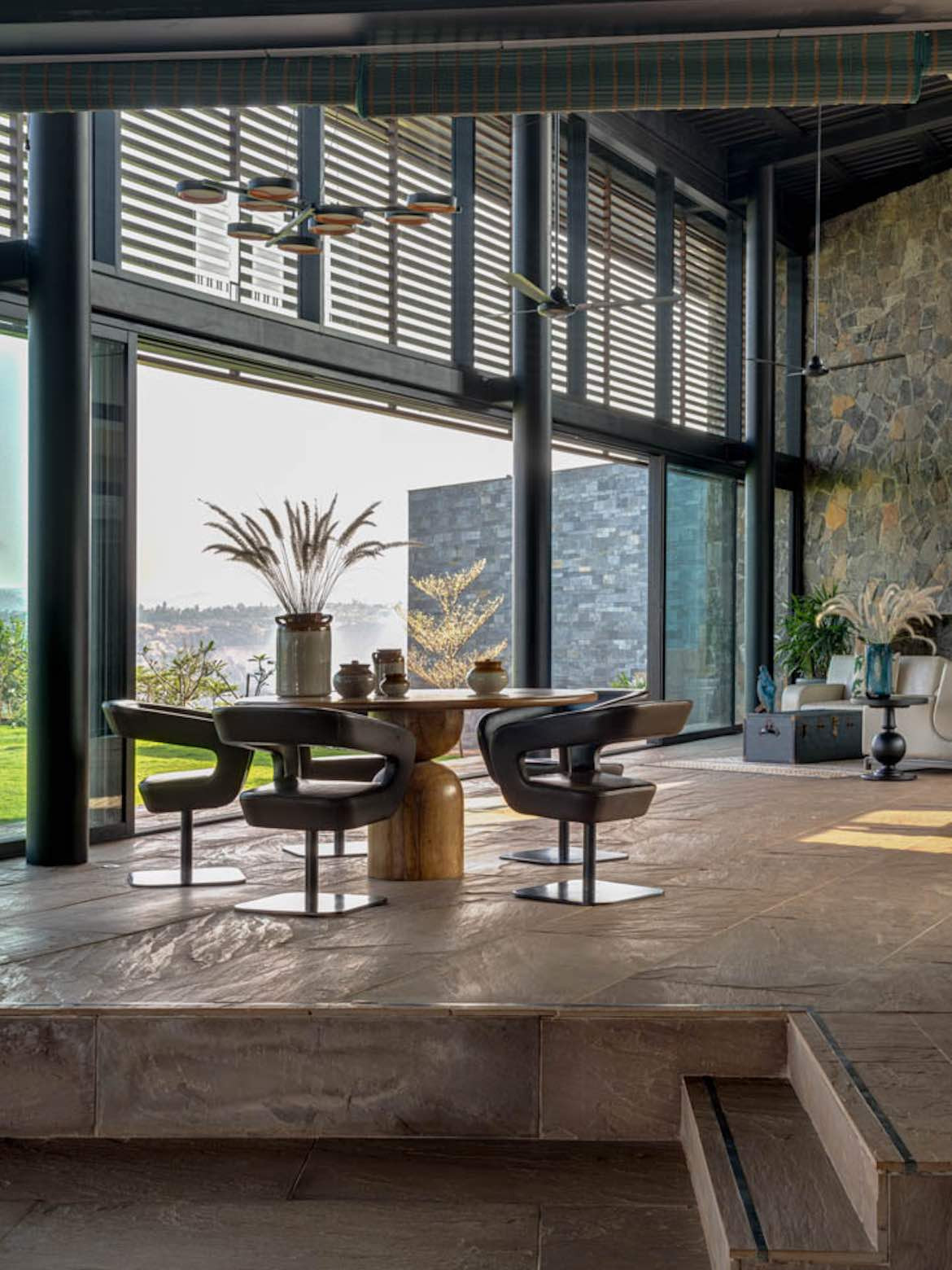 Four modern chairs sit around a dining table near large windows in the living area of Airavat.