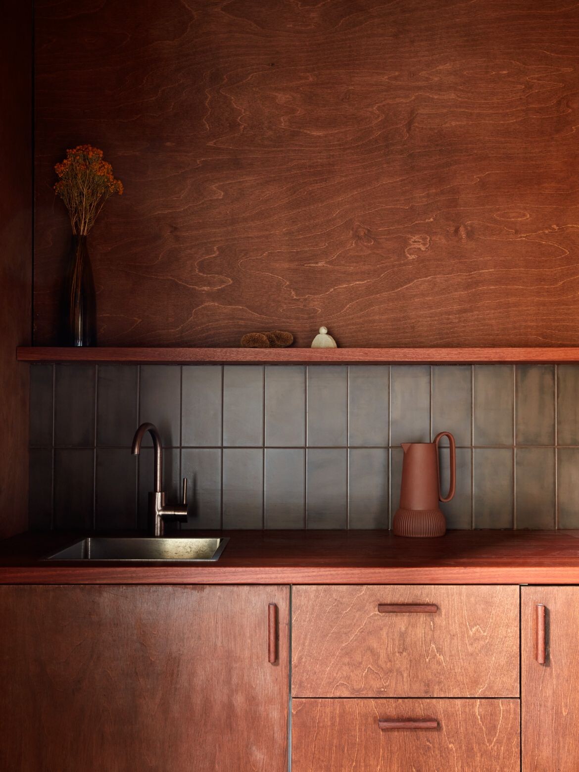 A dark-tinted plywood kitchen at Grotto Studio's Shadow House