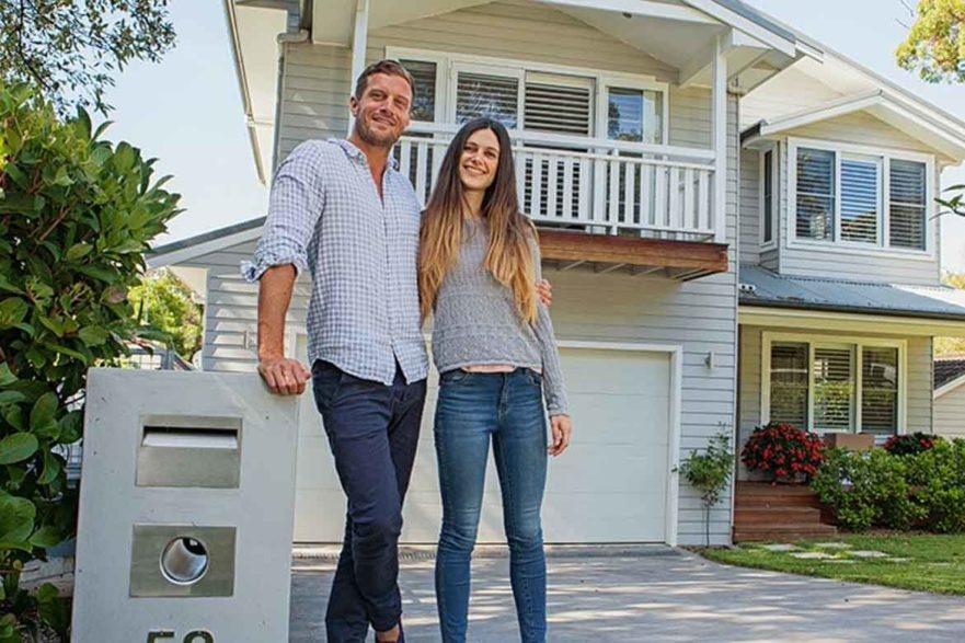 couple standing outside new home bought real estate