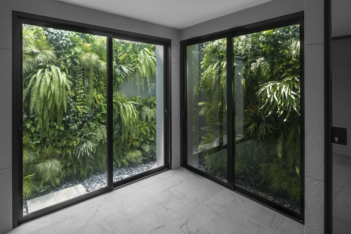 An internal corner of 55 Sathorn with windows on each side, looking out to dense greenery.