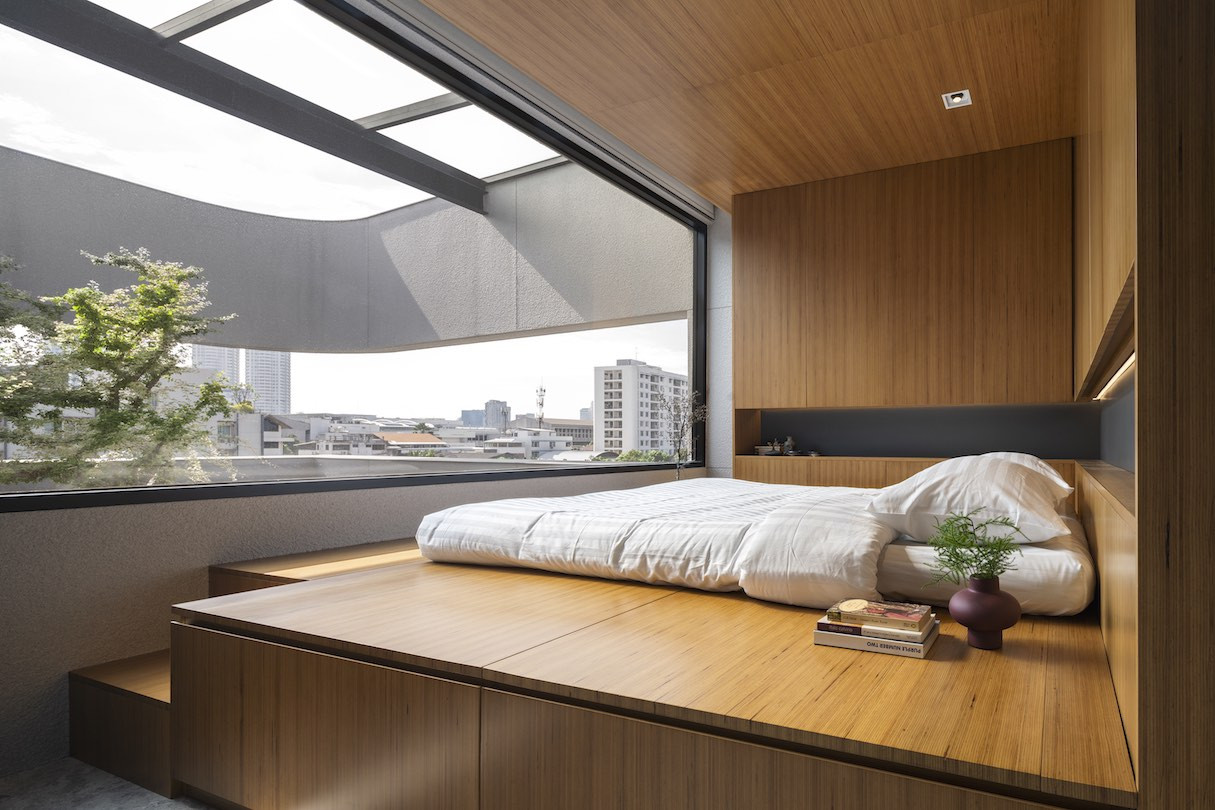 A platform bed with a view out to 55 Sathorn's tree.