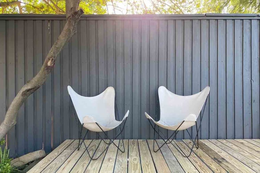 black timber fence painted timber dark colours sophisticated moody with chairs and natural timber deck architect's home