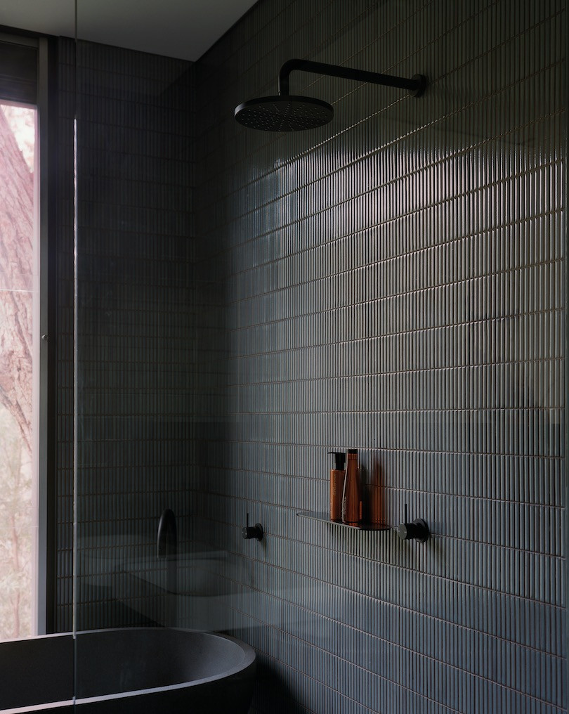 Thin dark grey-blue tiles cover the bathroom in Pearl Beach House