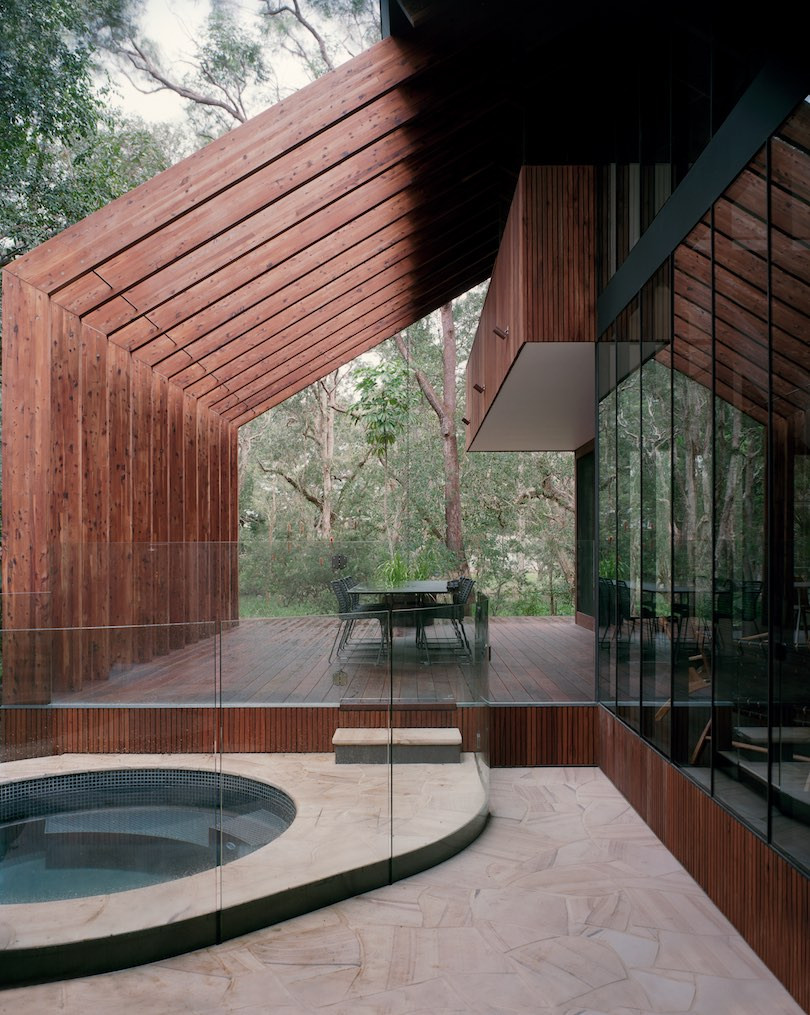 A wood deck with a table and chairs, and a green tiled spa in Pearl Beach House.