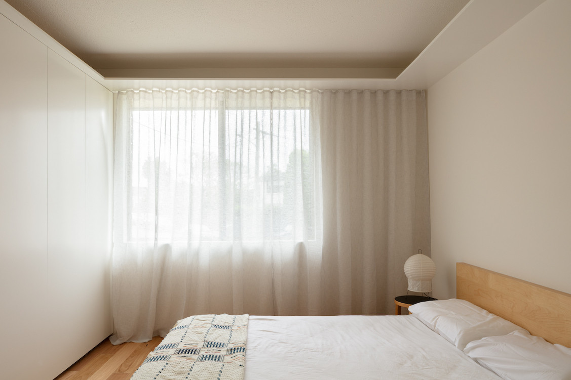 Bedroom with sheer curtains and blackbutt floors.