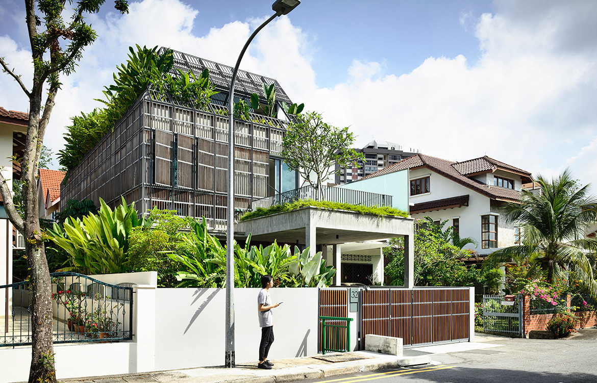 Streetscape of Fade To Green by HYLA Architects a concrete house clad in an aged chalky-grey trellis with tropical plants poking out