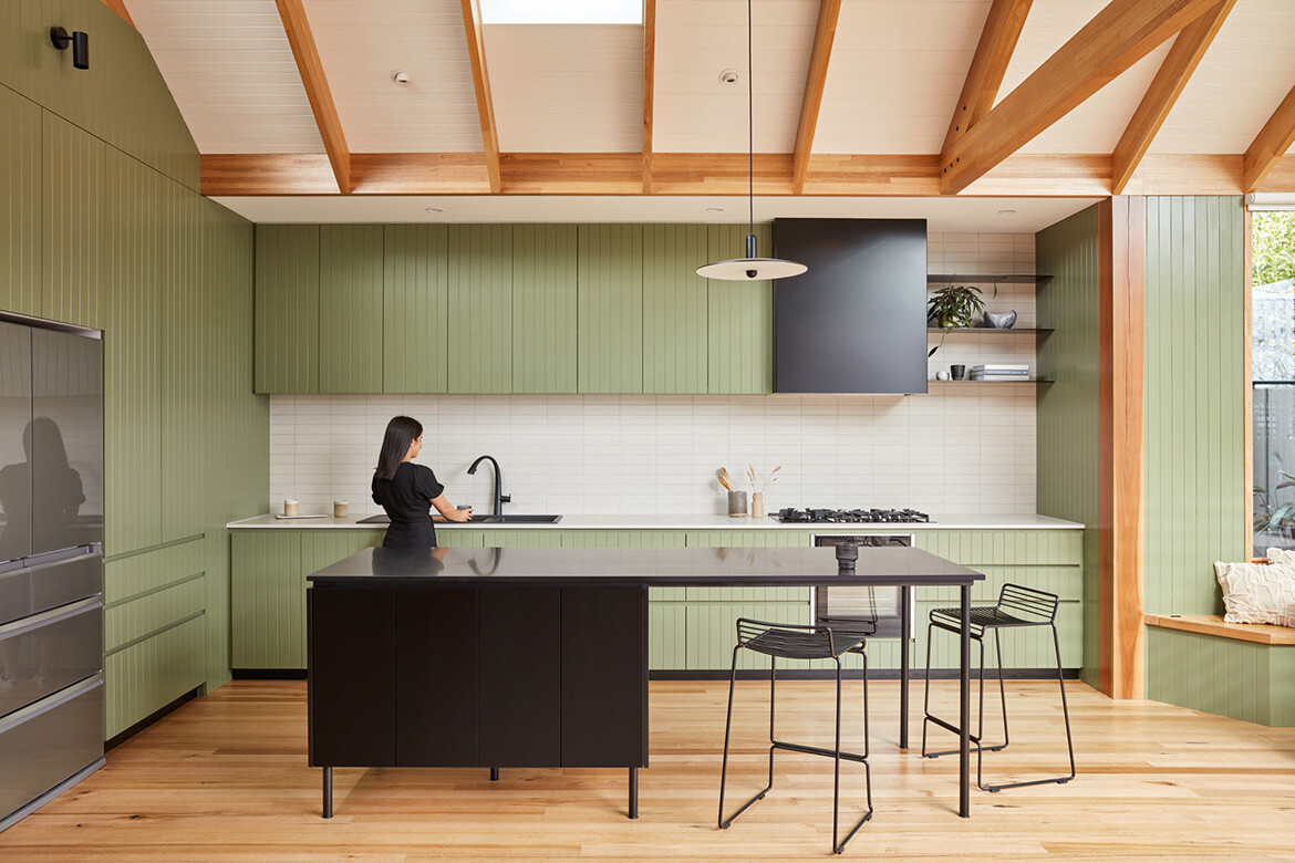 The kitchen at North King features a soothing green cabinetry that complements the timber floor