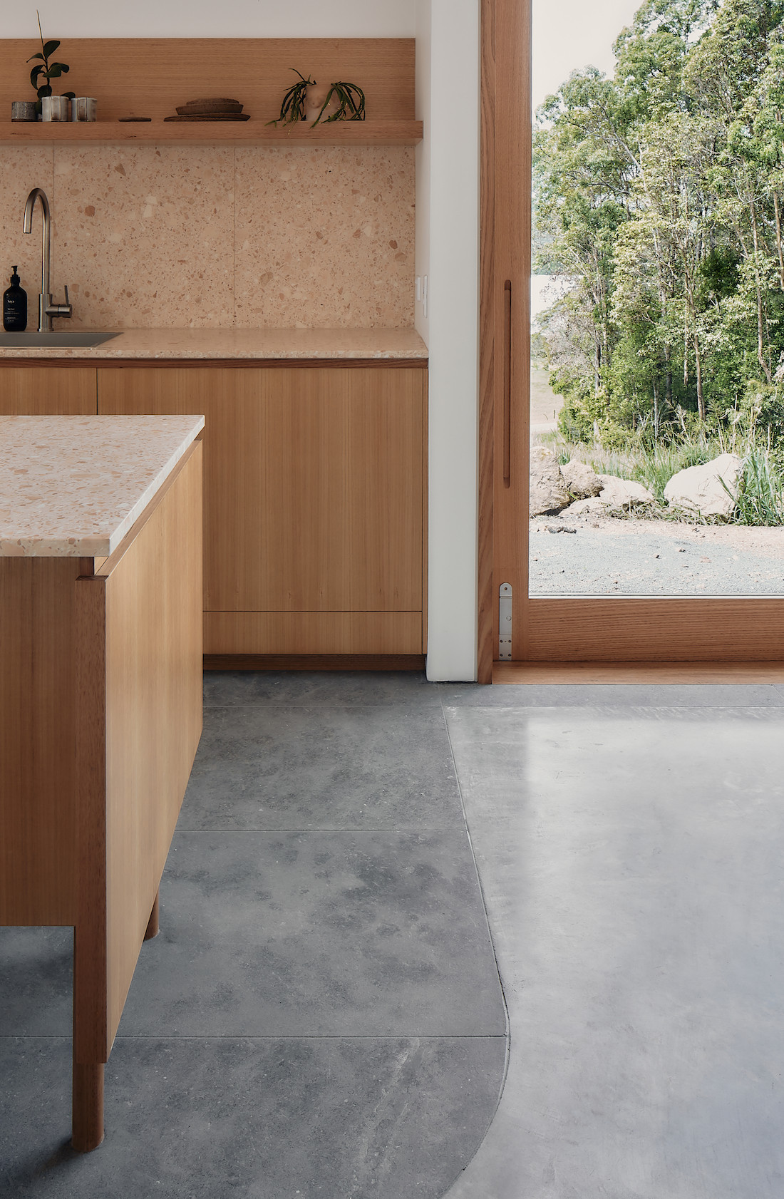 Limestone and concrete floors meet at the edge of the kitchen in A-CH's Yandina Sunrise Sunshine Coast hinterland home.