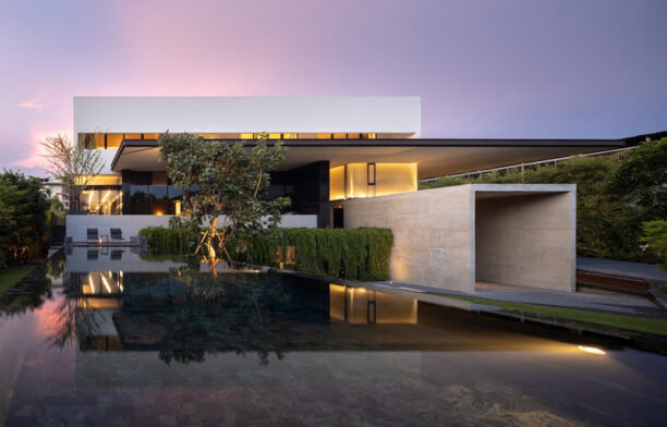 The sunset over the white exterior of Casa Cloud by Boondesign, with the reflective pool in the foreground.