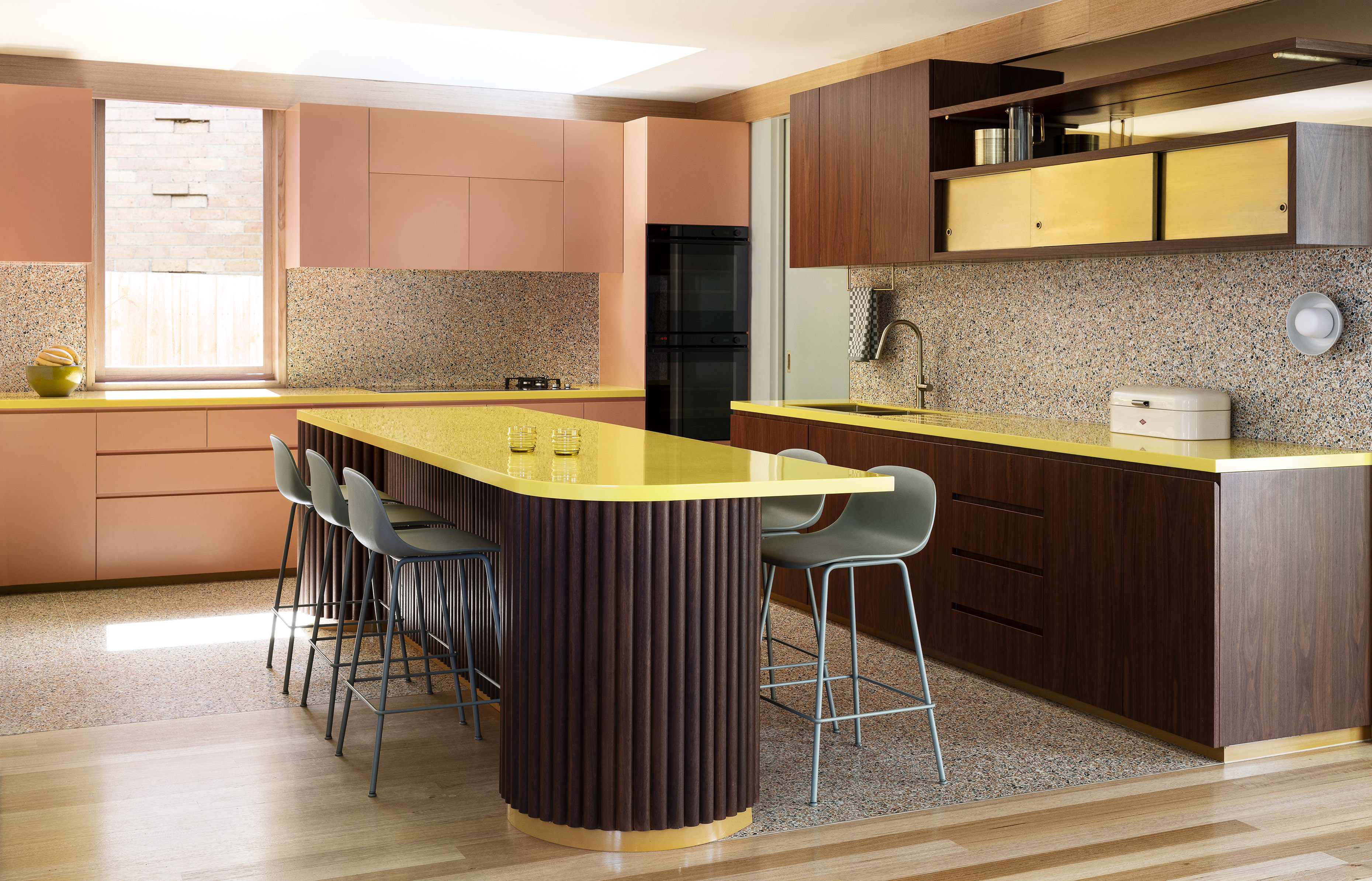 Colourful kitchen with yellow benches, pink cabinets and terrazzo floors by Wowowa