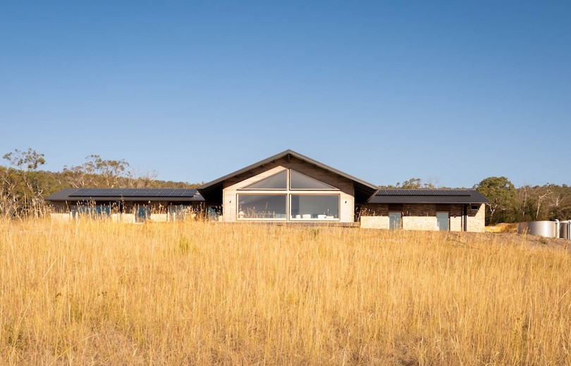 Wheat-like grass runs up the hill leading to Thinking Paddock House by Open Creative Studio.