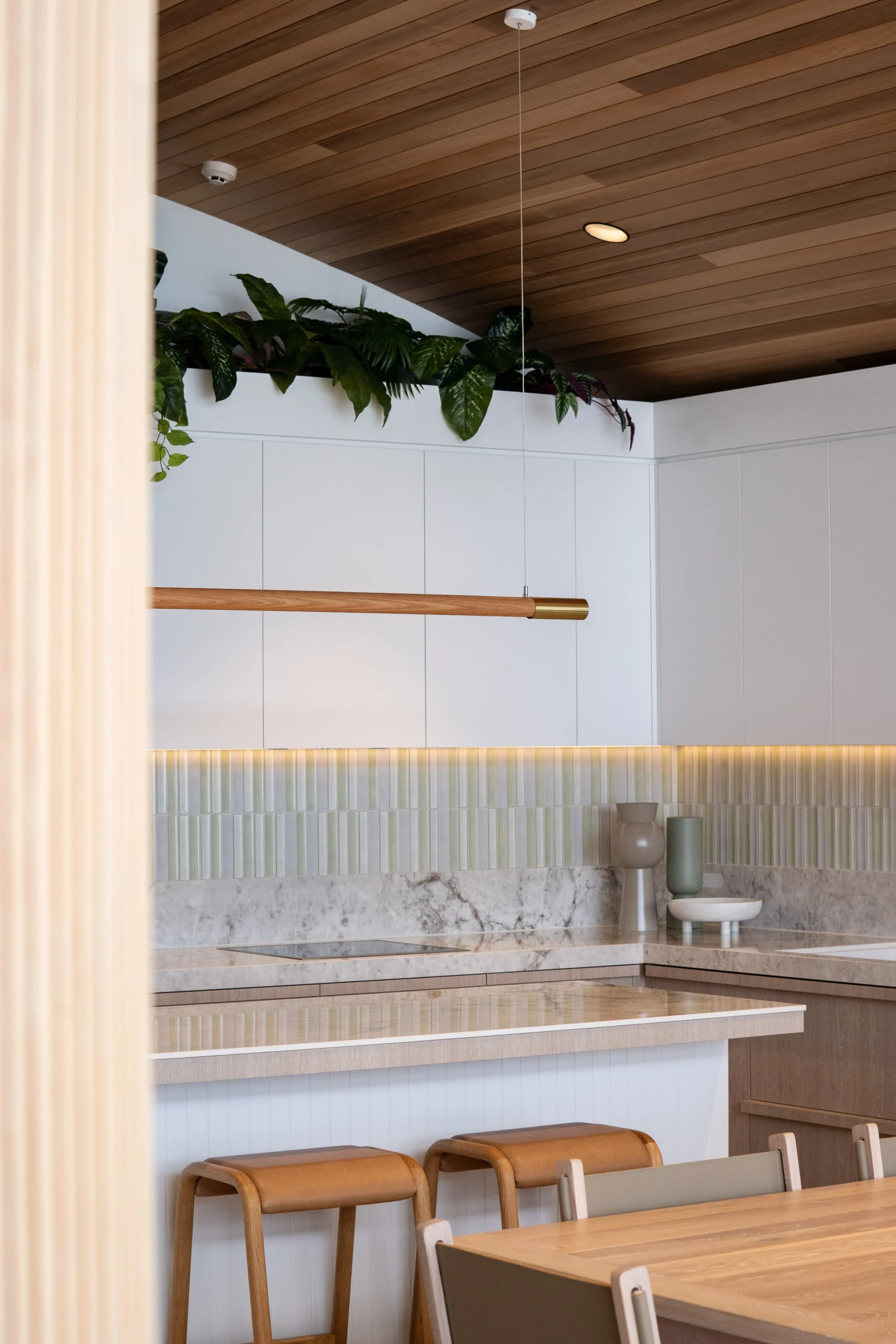 A coastal penthouse kitchen with luxe soft green stone and tiles