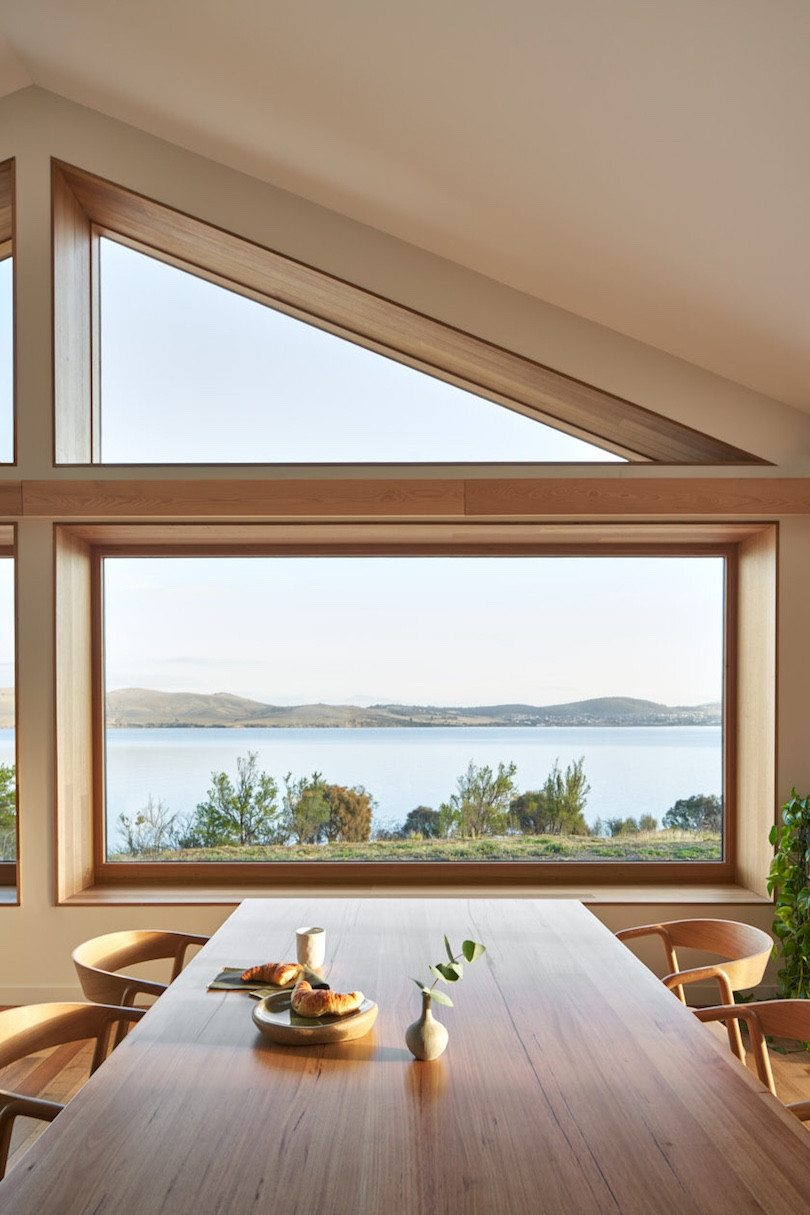 A dining table and Scandinavian-style dining chairs with the large window view in the background.