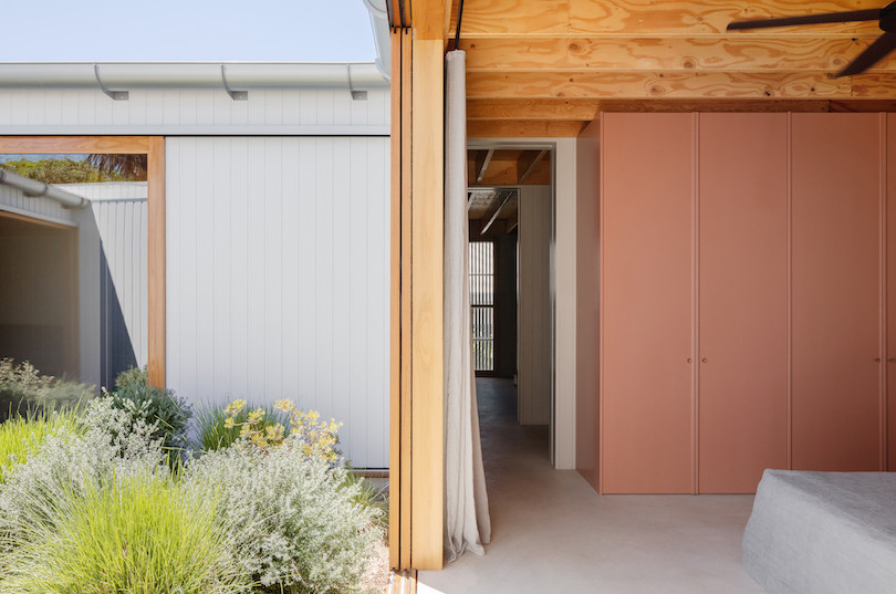 A bedroom with salmon coloured built-ins that looks onto the courtyard of Tribe Studio Architect's Bundeena Kit-home.