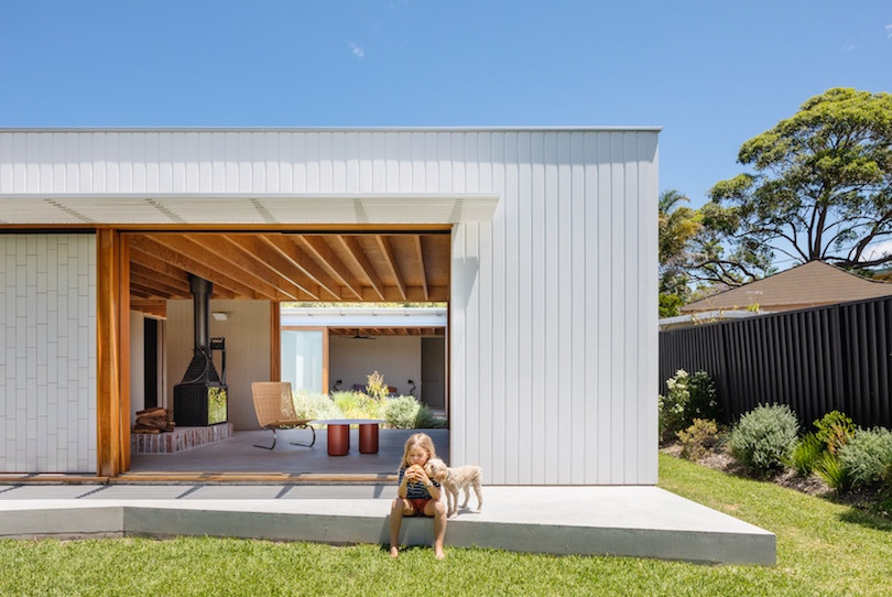 A child and a dog look at a burger outside Tribe Studio's Kit-home prototype.