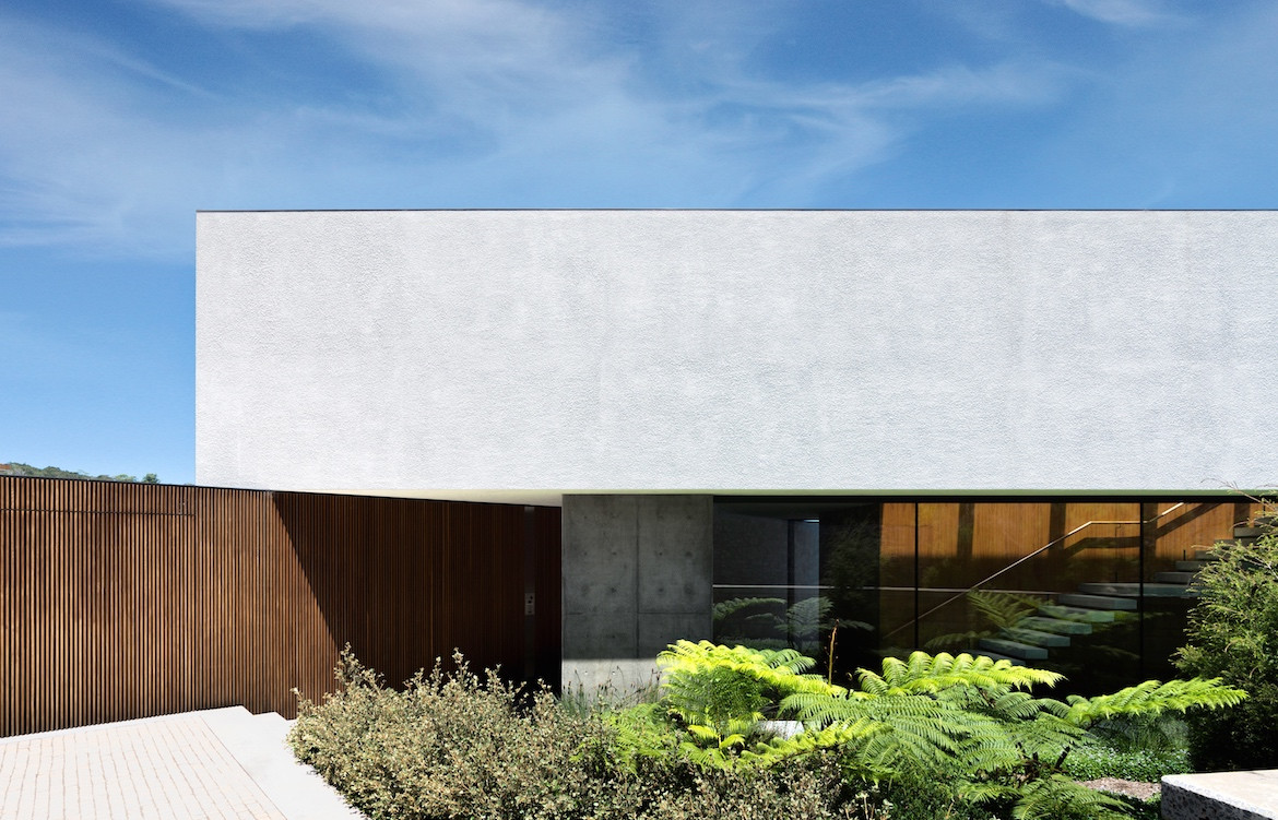 White exterior of Tobias Partners Collins Beach House with a blue sky background.