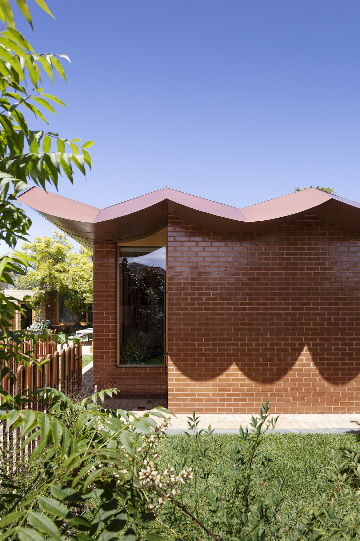 Inverted arched shadows on the glazed brick wall of the Wowowa designed home..